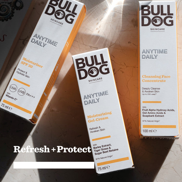 Three Bulldog Skincare boxes from the Anytime Daily Collection Bundle rest on a marble surface in sunlight. Products include Daily Face Moisturiser SPF 30, Moisturising Gel-Cream, and Cleansing Face Concentrate with natural origin ingredients. Refresh + Protect.