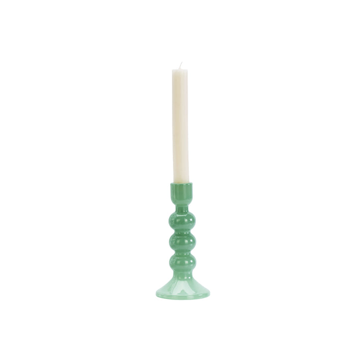 Green candle holder with a white candle on a white background