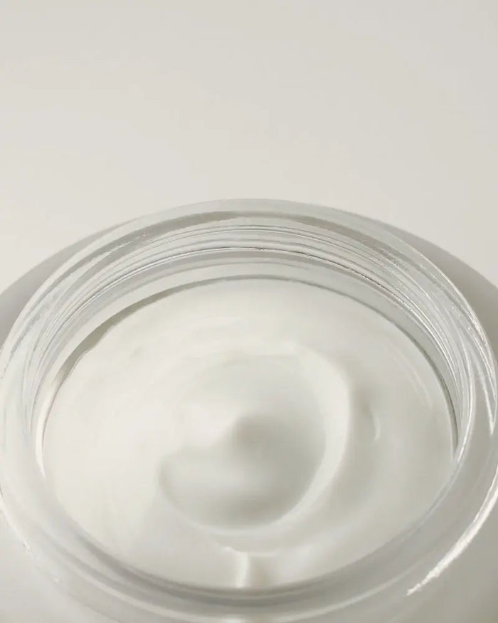 Close-up of a jar of white cream on a light gray background