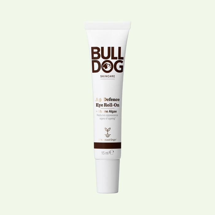 A tube of Age Defence Eye Roll-On for mens skincare, featuring marine algae to reduce signs of aging, stands upright on a light background. The white packaging displays brown and gold text.