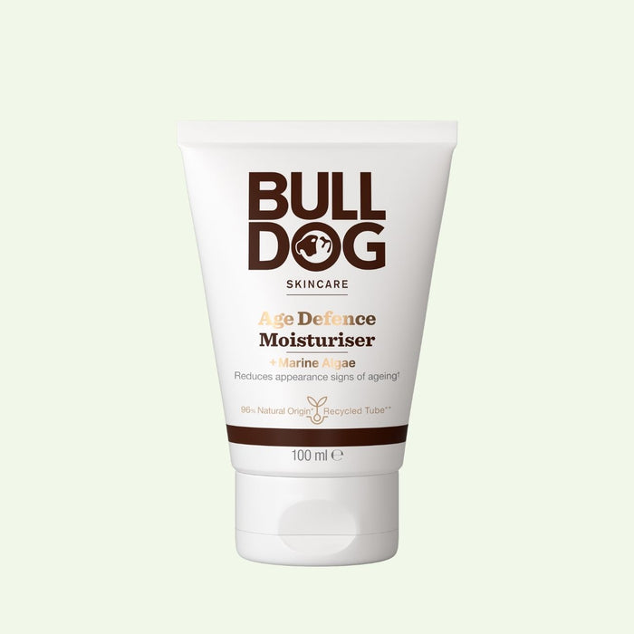 A 100ml white tube of Age Defence Moisturiser for men with natural origin ingredients and Marine Algae, featuring brown text and a white cap, is shown against a light background.