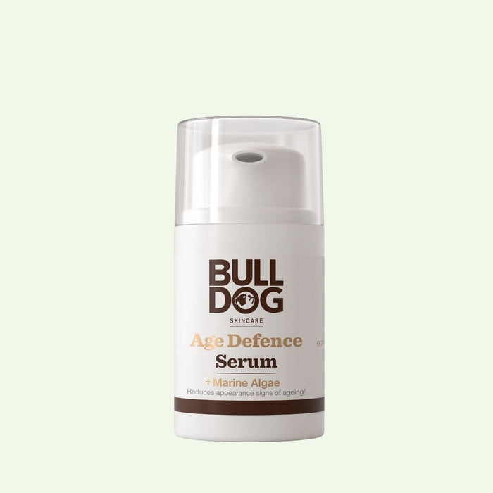 A bottle of Age Defence Serum with natural origin ingredients to target fine lines and wrinkles, shown with a white pump dispenser and clear cap against a pale green background.