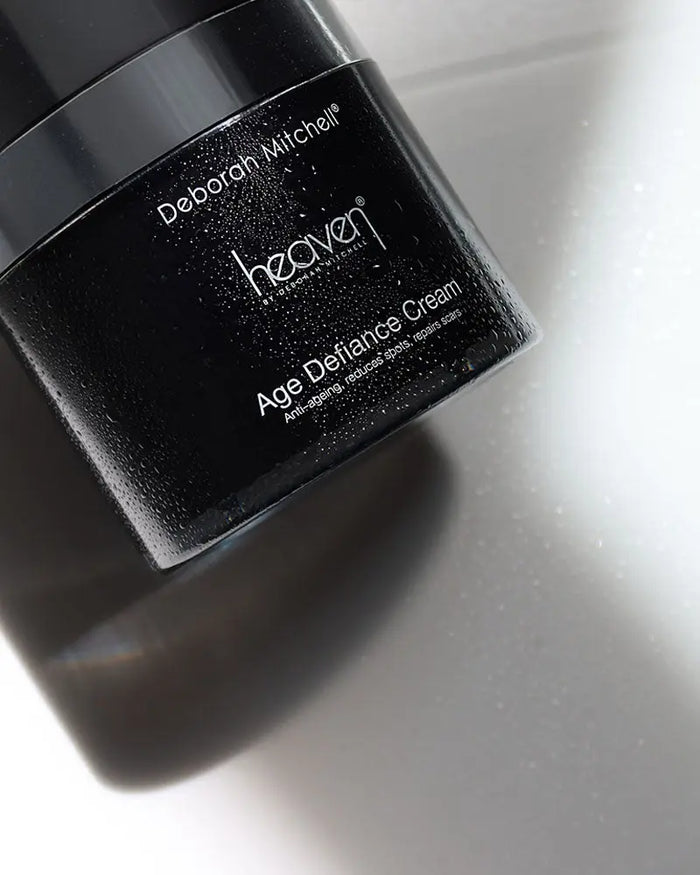 Black jar of Deborah Mitchell Heaven Age Defiance Cream on a reflective surface