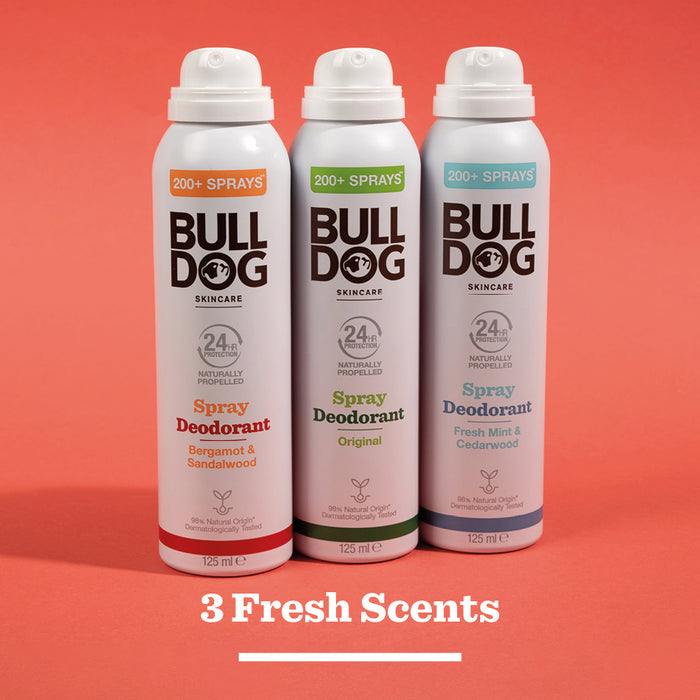 Three Bulldog spray deodorant cans—Bergamot & Sandalwood, Original, and Fresh Mint & Cedarwood—stand side by side on a red background; each is vegan and made with natural ingredients for fresh scent options.