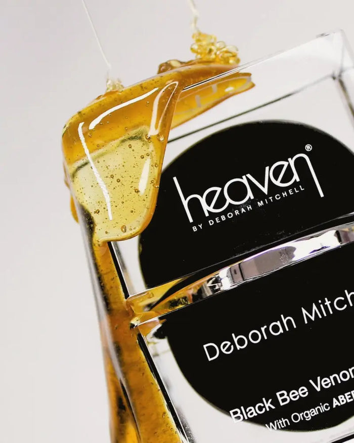 Deborah Mitchell Heaven Black Bee Venom product with honey dripped over the jar on a white background