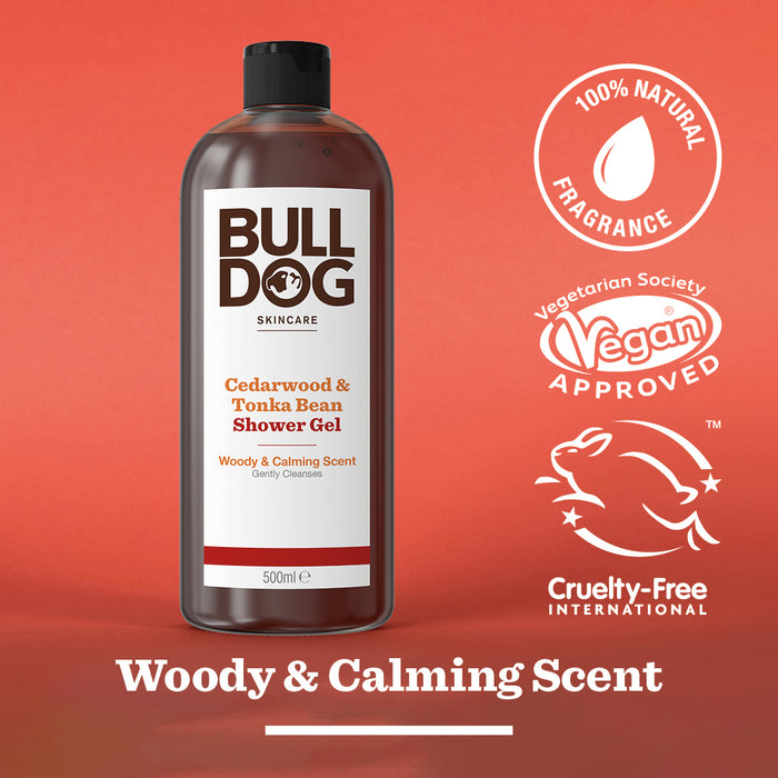 A bottle of Cedarwood & Tonka Bean Shower Gel sits on a red background, labeled 100% natural fragrance, vegan approved, and cruelty-free. Text reads: Woody & Calming Scent.