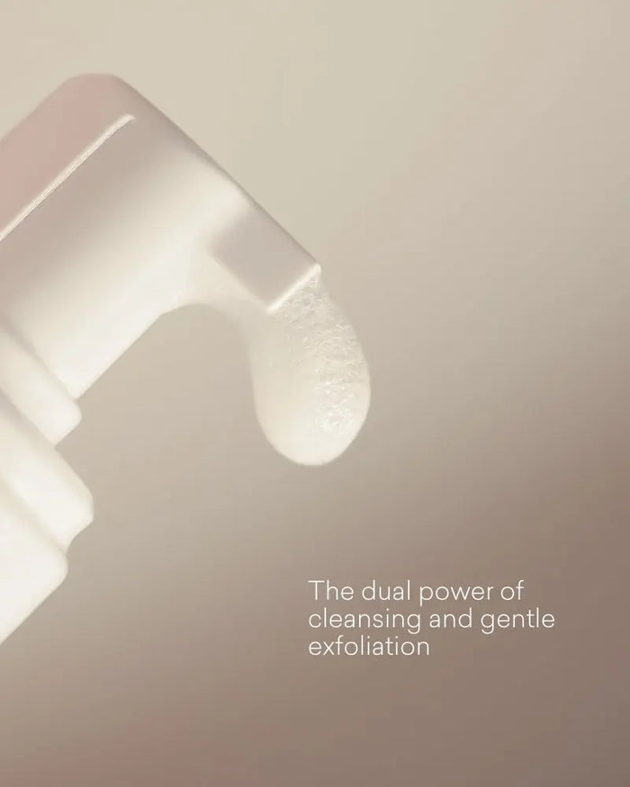 Close-up of the foam coming out of the pump with text 'The dual power of cleansing and gentle exfoliation' on a beige background.