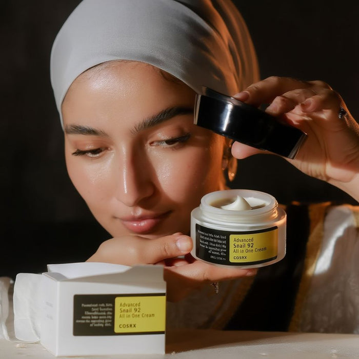 Person applying a skincare product to their face with a focus on the cream jar.