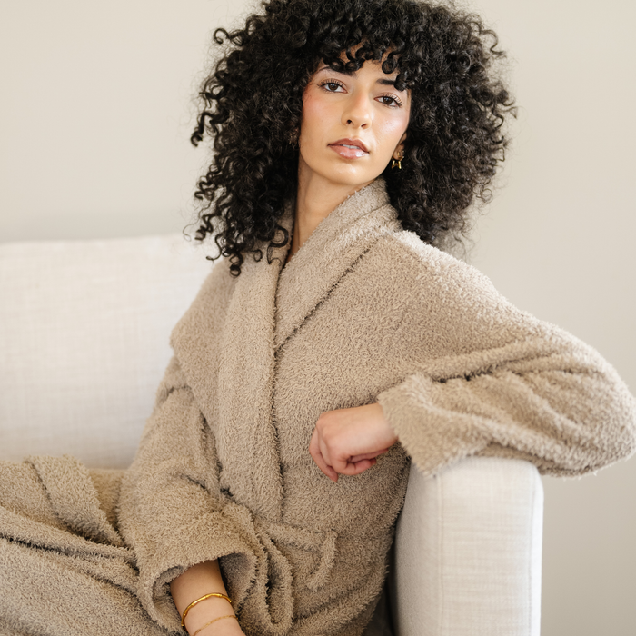 Woman sitting on couch wearing taupe bamboni cozy robe.