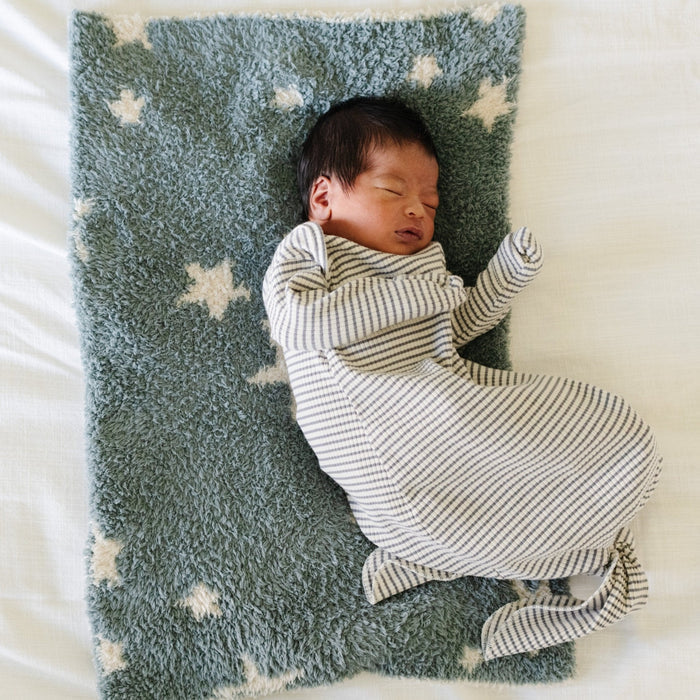 A baby boy lays on a double-layer Bamboni® baby blanket. The plush, breathable blanket features a two-tone blue and cream star design, offering ultimate softness and warmth. Made from Saranoni’s signature stretchy, cloud-like Bamboni® fabric, this luxury baby blanket provides comfort for naps, tummy time, and on-the-go snuggles. The perfect blend of warmth and breathability, it’s a must-have for parents seeking high-quality, ultra-soft blankets. The soft blanket is a mini blanket and Saranoni bl
