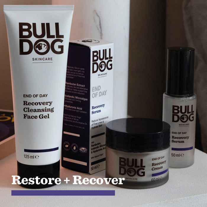 A set of Bulldog Skincare products, including the End of Day Recovery Cleansing Face Gel with Turmeric Extract, recovery serum, and recovery cream, arranged on a surface with a box and the words Restore + Recover below.