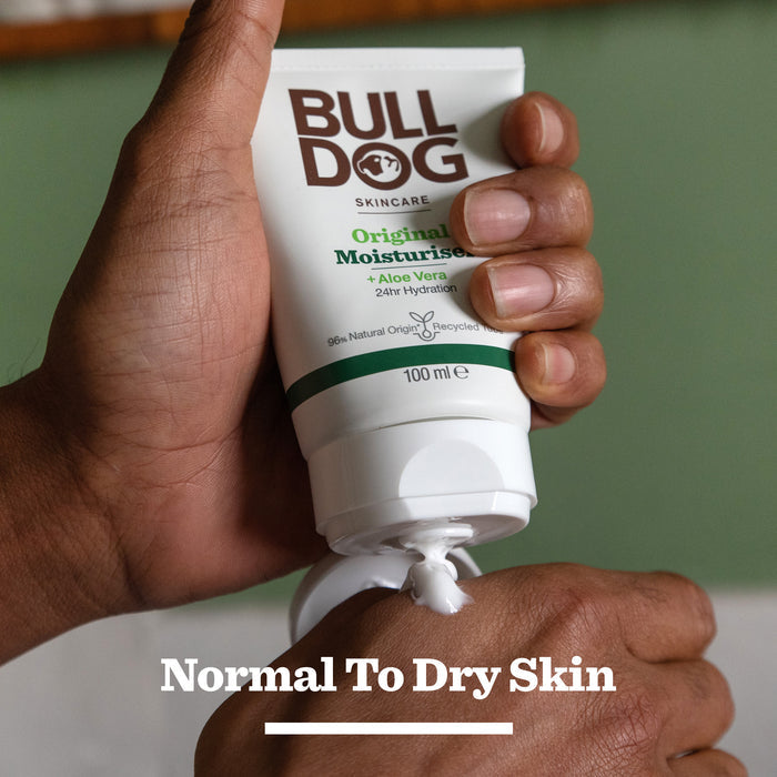 A hand squeezes Bulldog Skincare for Men Original Moisturiser onto the fingers, with text reading Normal To Dry Skin. The recyclable tube features aloe vera and pairs perfectly with the Expert Shave Trio set.