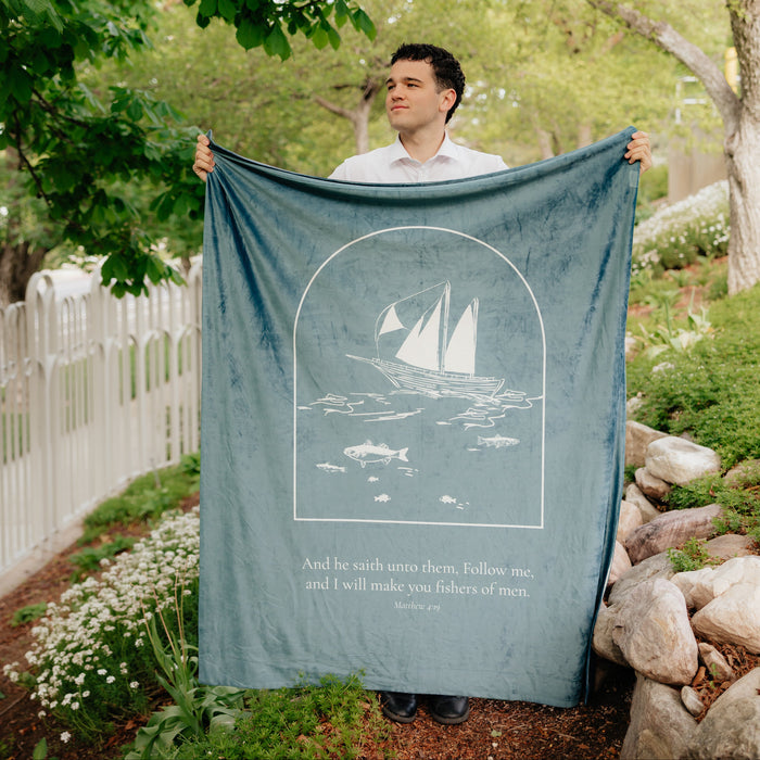 Man holding Fishers of Men Christian blanket featuring Matthew 4:19 scripture and sailboat artwork – faith-based Christian gift