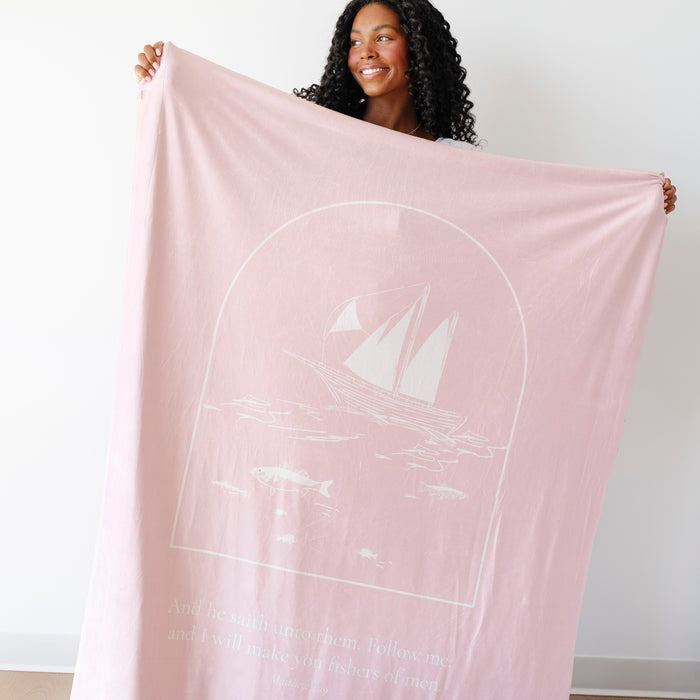 Woman displaying a rose Christian blanket featuring Fishers of Men artwork and scripture verse