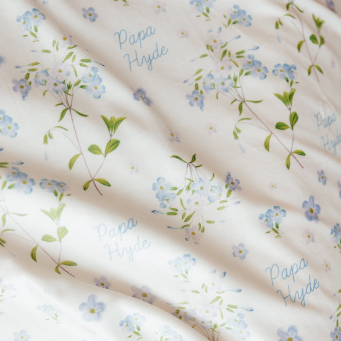 Close-up of a personalized Forget Me Not sympathy blanket featuring delicate blue forget-me-not flowers, soft botanical artwork, and a custom loved one's name woven throughout the design, meaningful memorial blanket created to honor and remember cherished memories.