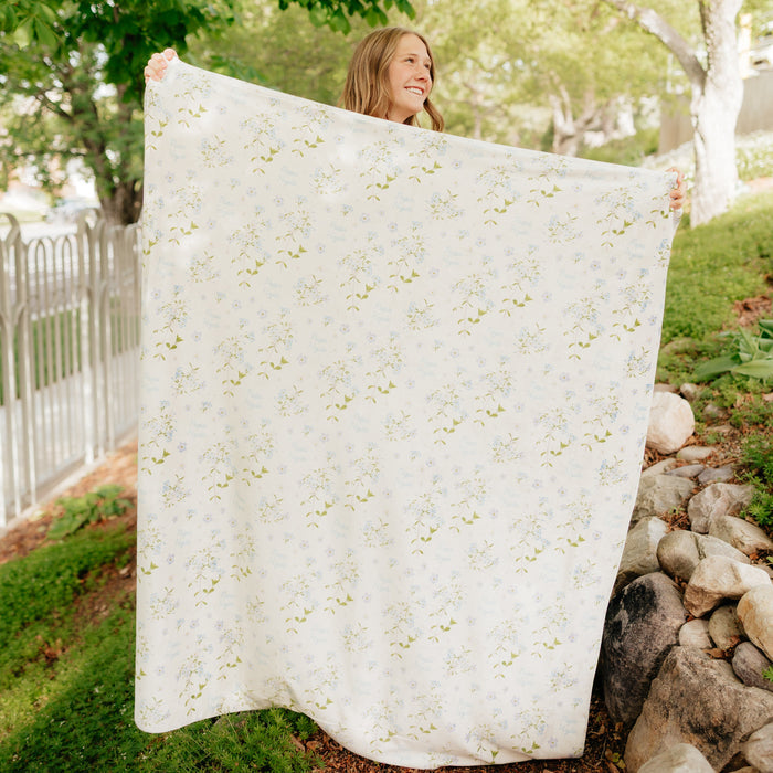 Person holding a personalized Forget Me Not sympathy blanket featuring delicate floral artwork and a custom name, meaningful memorial gift blanket offering comfort, remembrance, and support during times of loss.