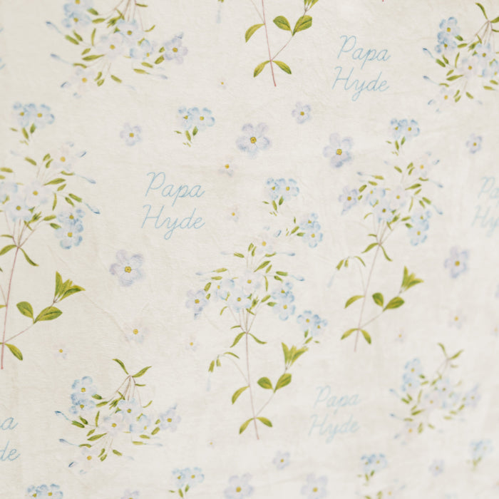 Close-up of a personalized Forget Me Not sympathy blanket featuring delicate blue floral artwork and a custom name woven throughout the design, meaningful memorial blanket created to honor and remember loved ones.