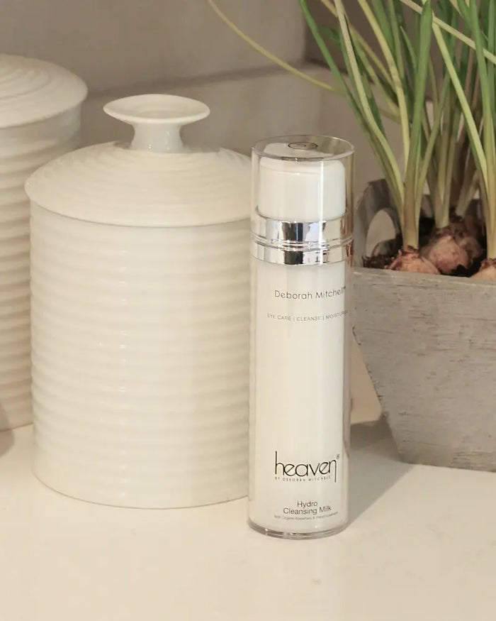 Skincare bottle hydro cleansing milk on a neutral background with ceramic jars in background