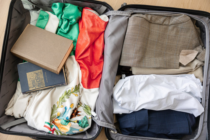 Personalized mission flag blanket packed in a missionary suitcase alongside scriptures and essentials, ready for LDS missionary service.