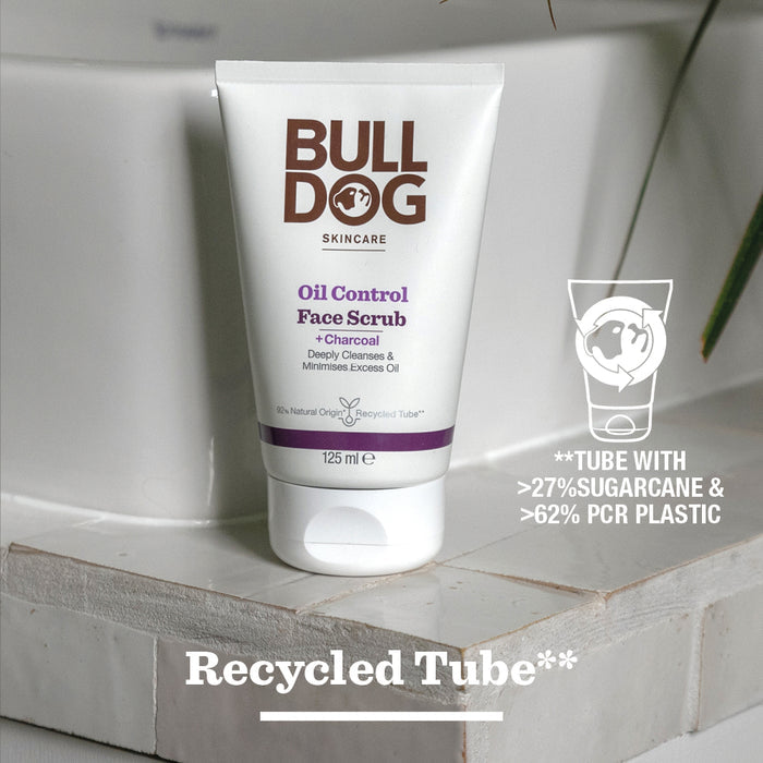 A tube of Oil Control Face Scrub rests on wood, highlighting its charcoal and natural origin ingredients. The packaging contains 27% sugarcane and 62% recycled plastic.