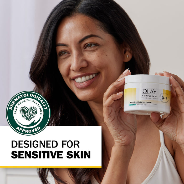 Model posing with Olay Complete + Rich Moisturizing Cream container smiling. Sensitive Designed for sensitive skin. Dermatologically approved.