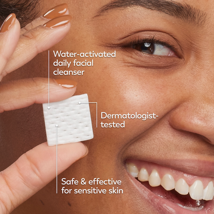 Model posing and smiling while holding melts cleanser swatch. Water activated daily facial cleanser. Dermatologist tested. Safe and effective for sensitive skin