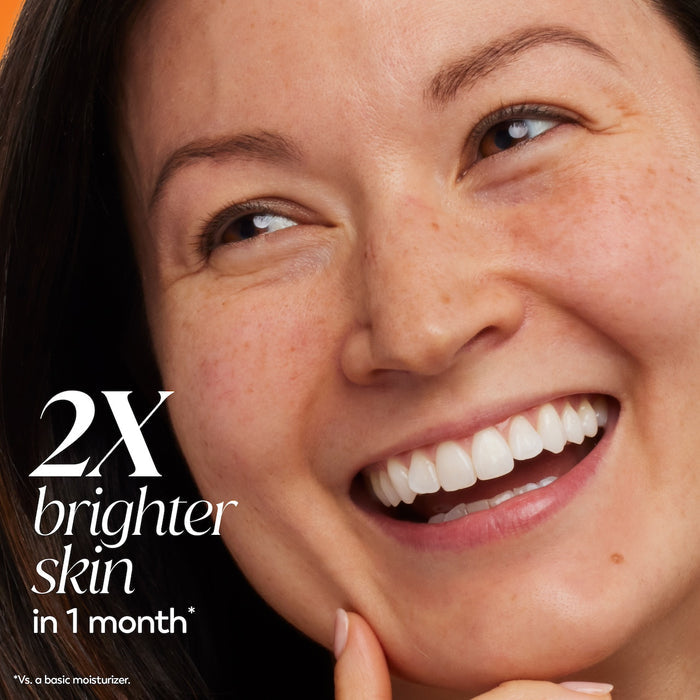 Model posing smiling. 2x brighter skin in 1 month* *Vs a basic moisturizer.