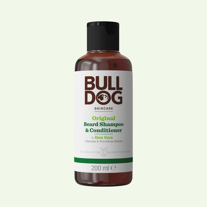 A 200 ml bottle of Original Beard Shampoo and Conditioner for men with natural origin ingredients and Aloe Vera, in a brown bottle with a black cap and a white label featuring green and brown text.