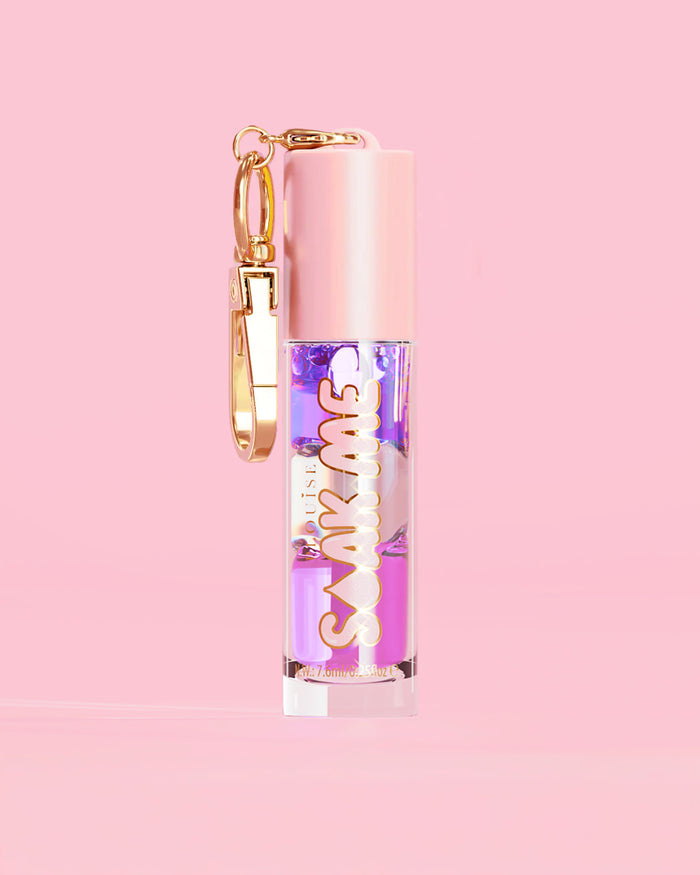 P. Louise Soak Me Lip Oil with colourful layered oil in a pink tube with a gold clasp on a pink background