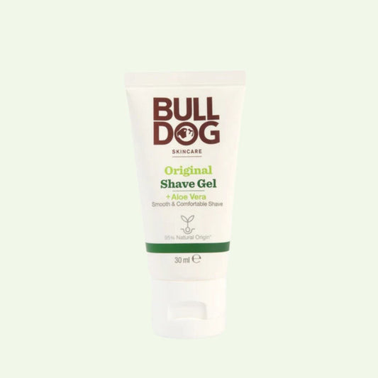 A white tube of Travel Original Shave Gel Mini (30 ml) with Aloe Vera stands upright on a light green background. The men's packaging highlights “smooth & comfortable shave” and “95% natural origin.”.