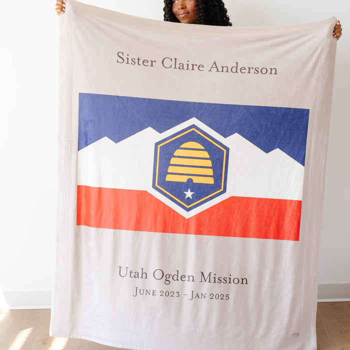 Person holding a personalized missionary blanket featuring a custom mission flag, missionary name, and service dates, meaningful LDS missionary gift for mission farewells, homecomings, and missionary families.