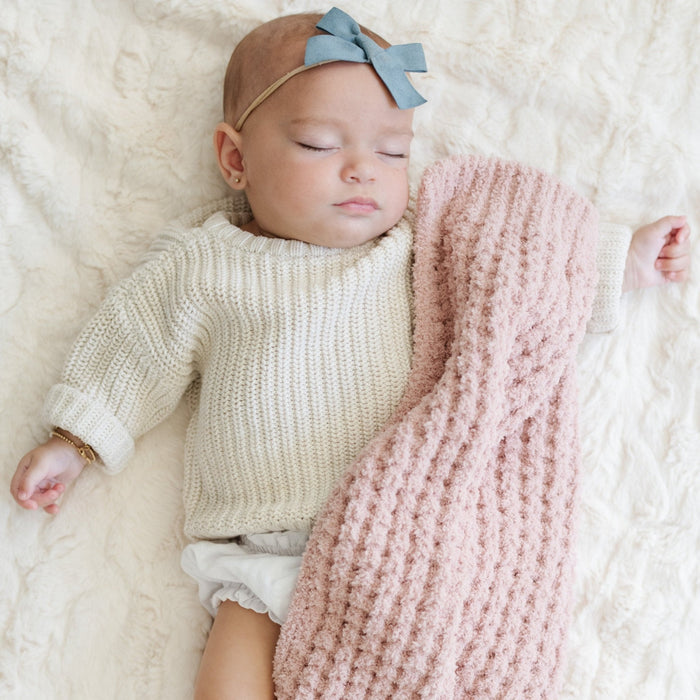 Baby girl sleeping with pink waffle knit mini blanket.