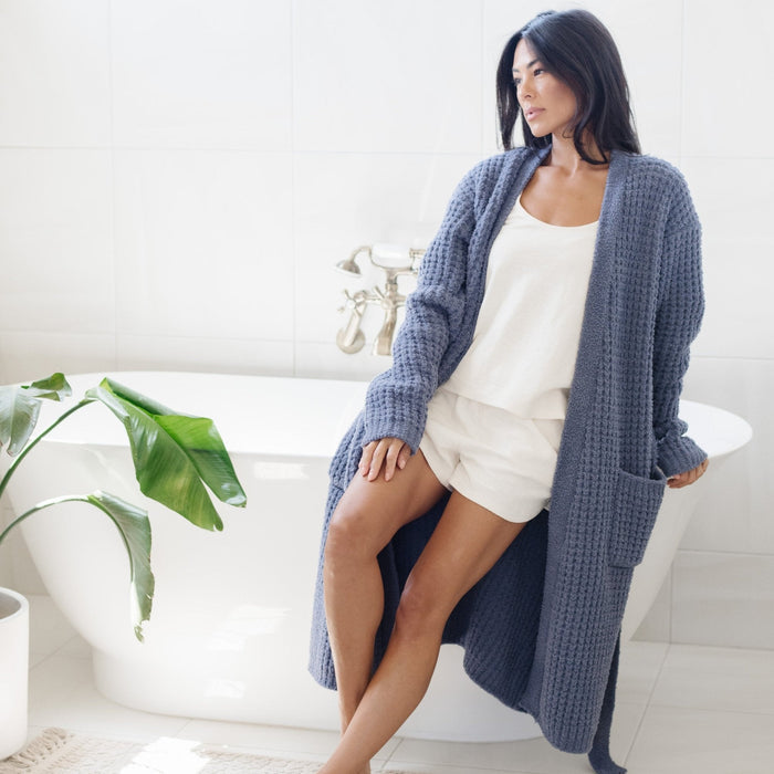 Woman in luxurious bathroom wearing cozy, blue waffle knit robe.