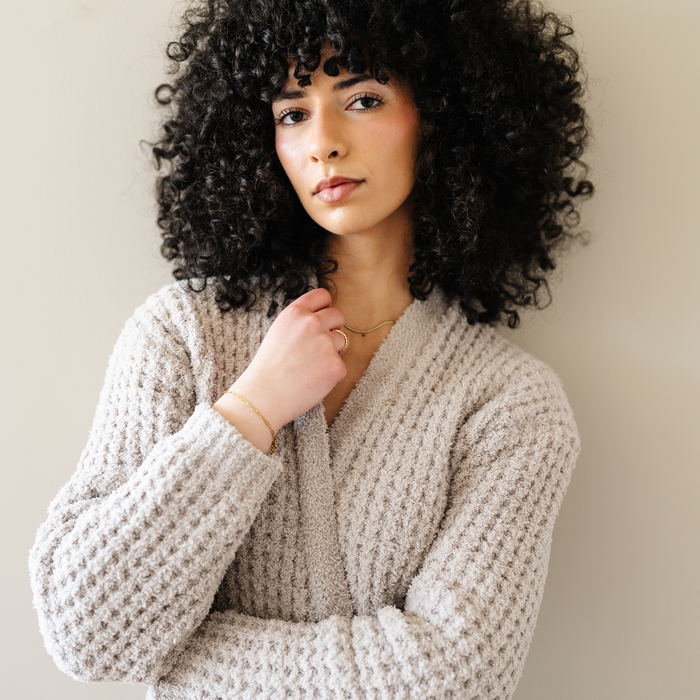 Woman wearing a tan oatmeal colored robe that is waffle knit.