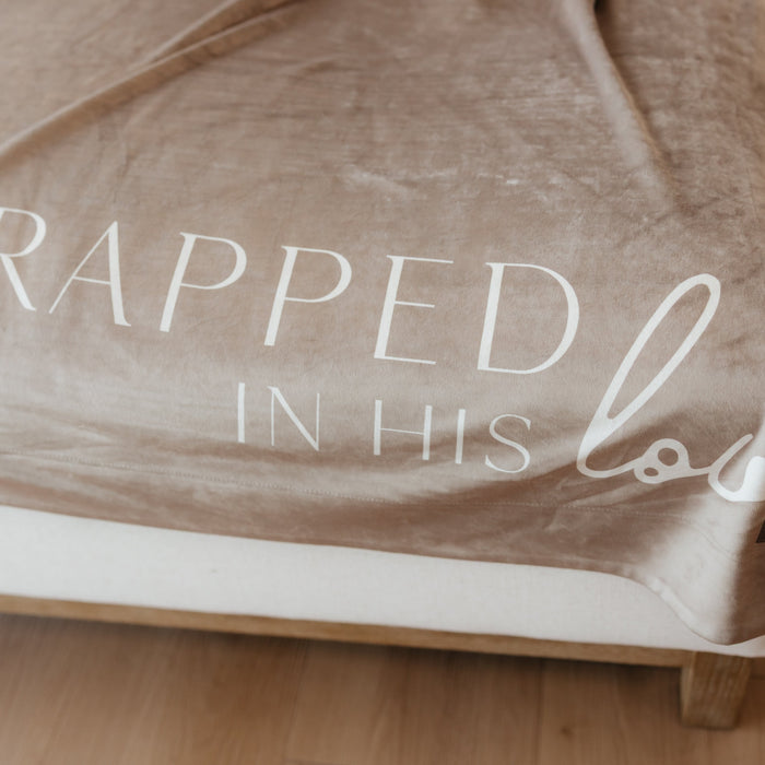 Close-up of a cocoa brown Christian blanket featuring the words "Wrapped in His Love" in elegant script.
